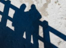 shadows of two people on a beach boardwalk