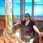 woman looking at camera from inside the glass of a lighthouse